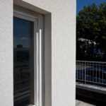 Scraped render finish to building exterior and around window reveal, railing to side of building