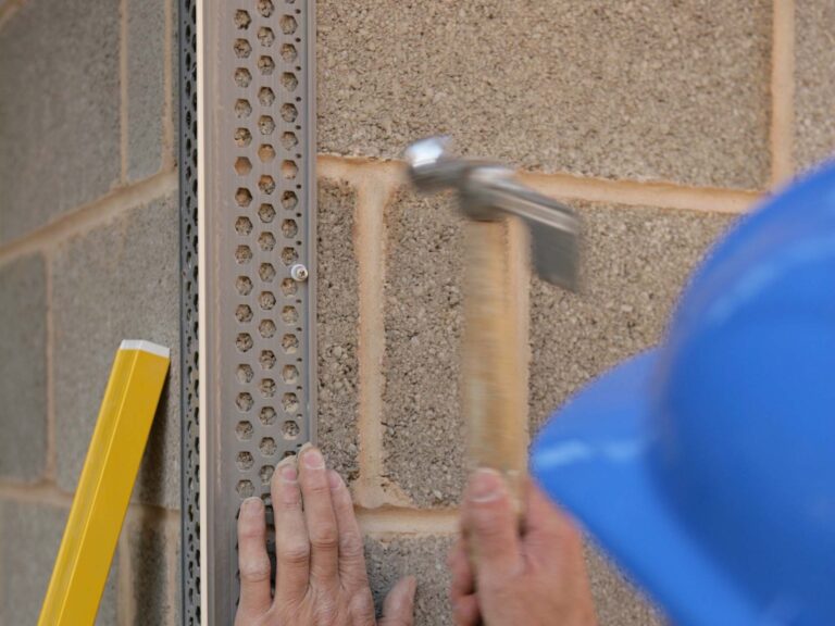 Close up of hammer-in fixings being applied to breeze block work on building exterior